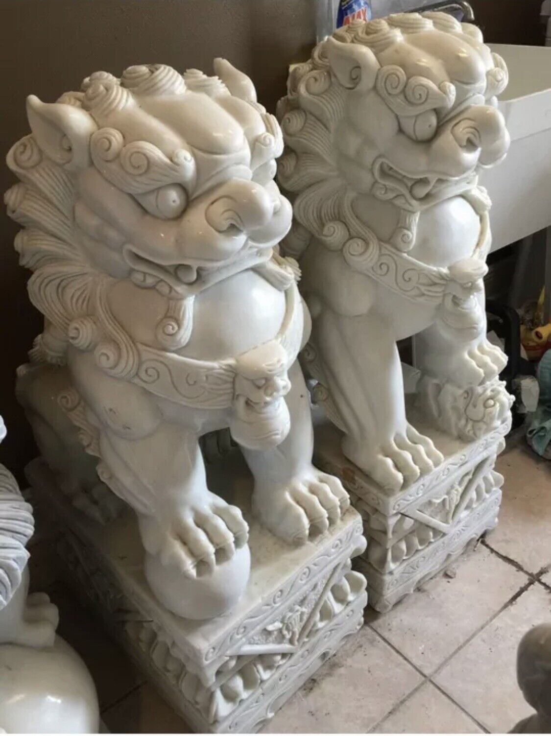 A pair of Chinese guardian lion statues made of genuine white stone.